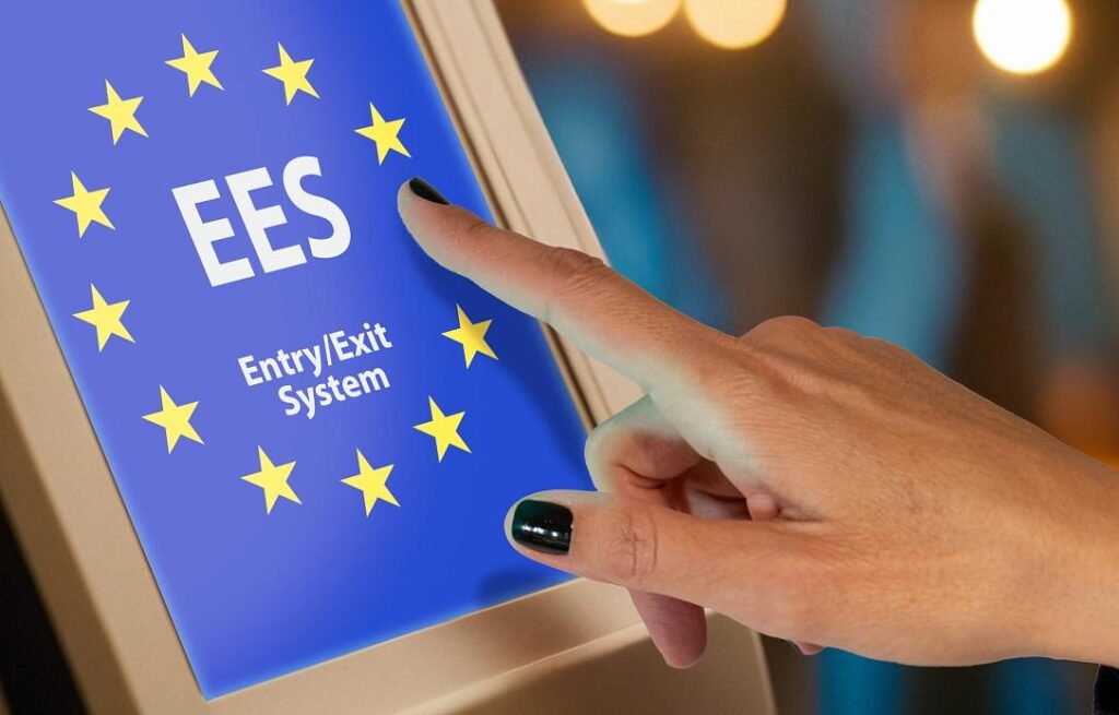 Рука касается экрана терминала EES с логотипом системы въезда-выезда ЕС и звёздами