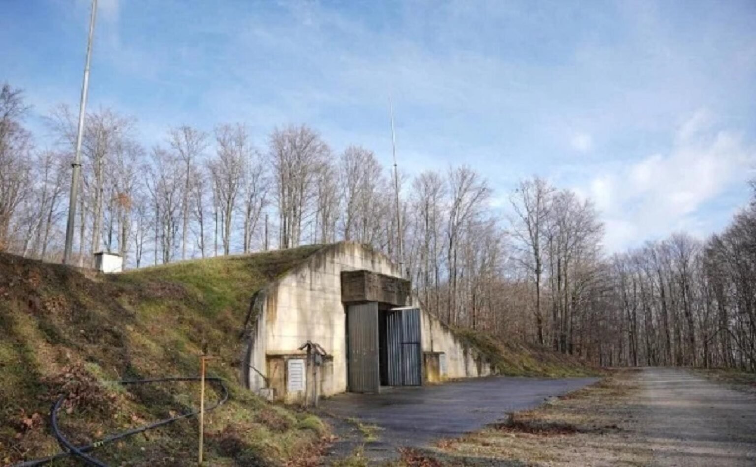 Подземный бункер-хранилище на объекте Трговска Гора с видимым входом, окружённый лесом