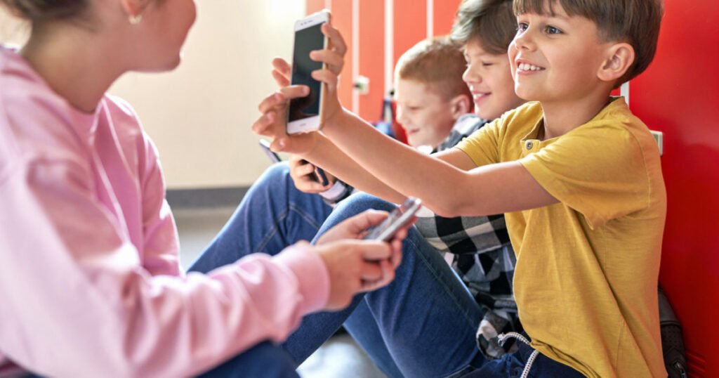 Дети со смартфонами в школьной обстановке, делают селфи и общаются
