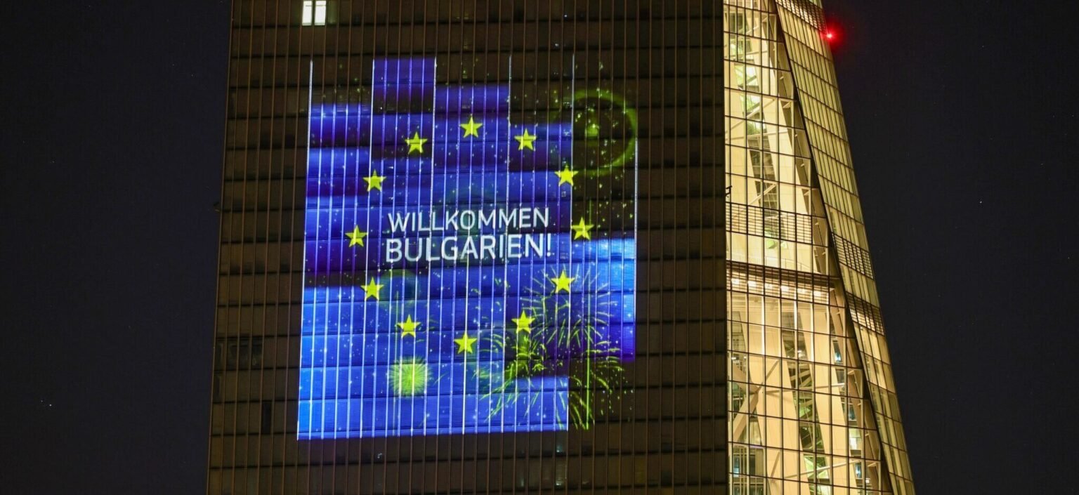 Здание ЕЦБ с проекцией «Willkommen Bulgarien!» и звёздами флага ЕС ночью