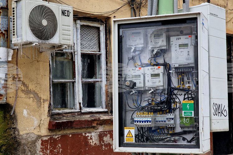 Электрические счётчики и проводка на стене здания с сосульками — иллюстрация энергетической инфраструктуры Болгарии