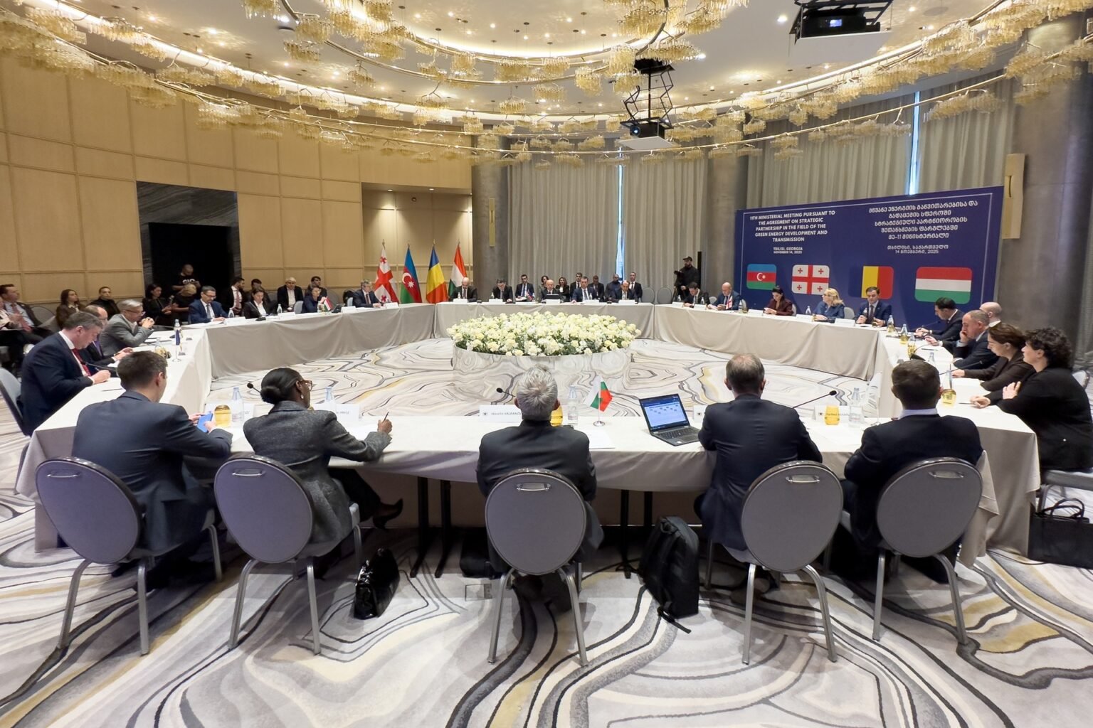 Общий план 11-й министерской встречи в Тбилиси (Грузия) с делегатами за круглым столом и флагами Азербайджана, Грузии, Румынии, Венгрии и Украины