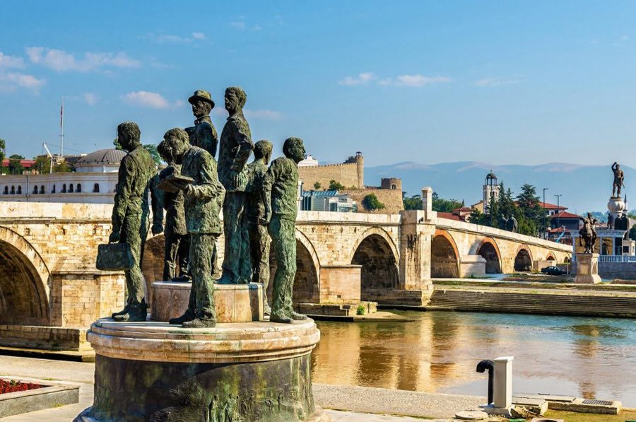Скопье: вид на Каменный мост через реку Вардар с бронзовыми статуями на переднем плане, крепость и горы на заднем плане