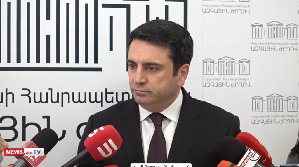 Спикер парламента Армении Ален Симонян у трибуны с микрофонами на фоне Национального собрания