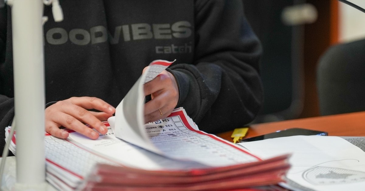 Крупный план: руки сортируют избирательные бюллетени во время пересчёта голосов на выборах в Косово