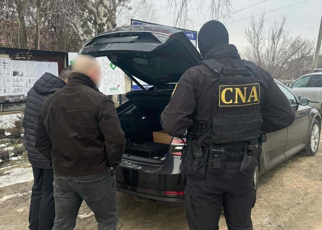 Сотрудник НЦБК в тактическом снаряжении проводит обыск багажника автомобиля