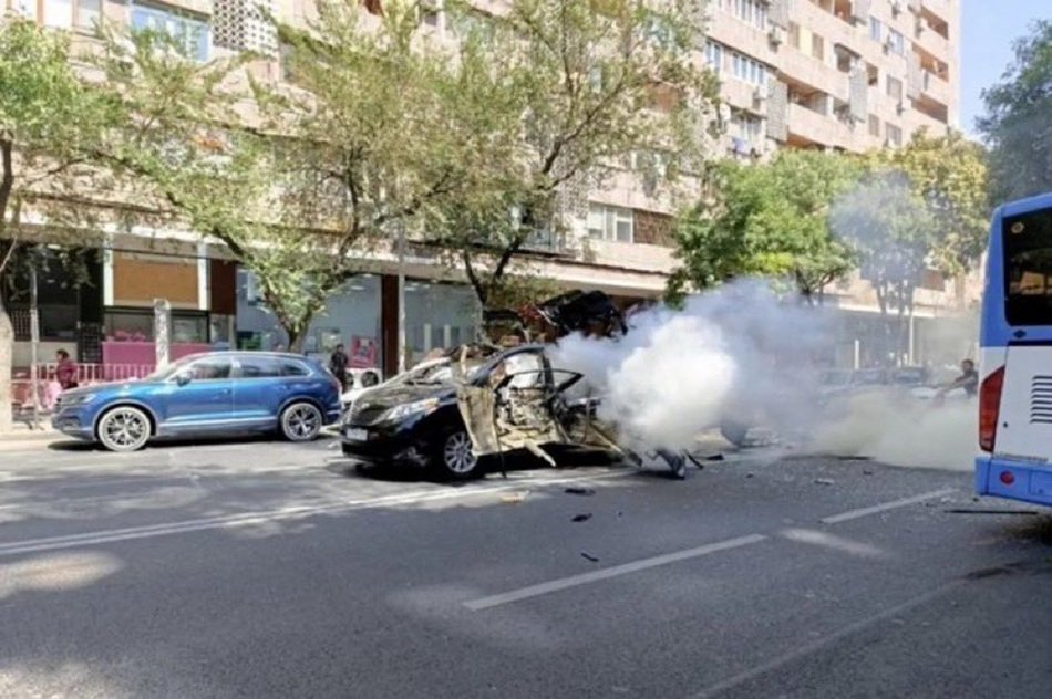 Взорванный автомобиль с дымом на улице - фото с места инцидента, показывающее последствия взрыва у посольства США