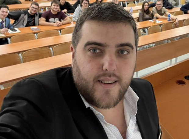 Экономист Любослав Костов в аудитории со студентами на заднем плане