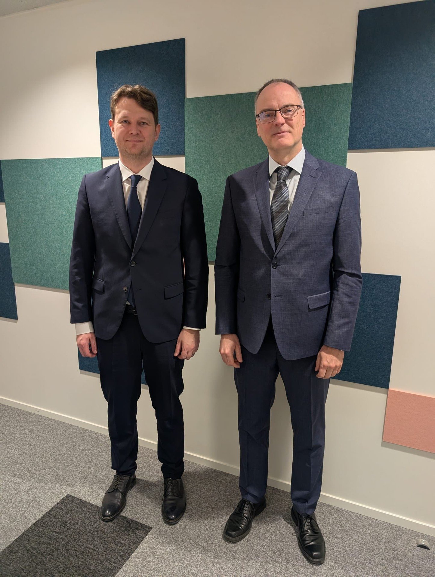 Министр финансов Гаврилицэ с другим чиновником на фоне цветных акустических панелей