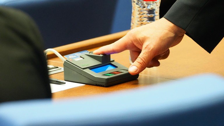 Close-up of an MP's hand pressing a parliamentary electronic voting device