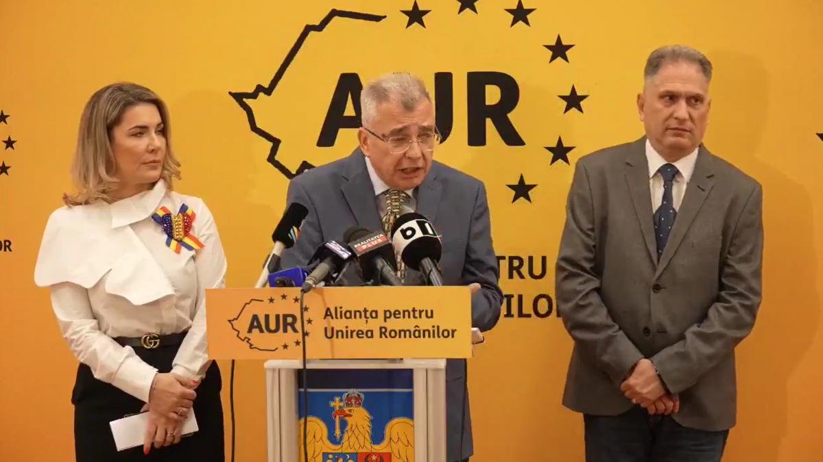 AUR (Alliance for the Union of Romanians) press conference announcing the three no-confidence motions, with party representatives at the podium against AUR party branding