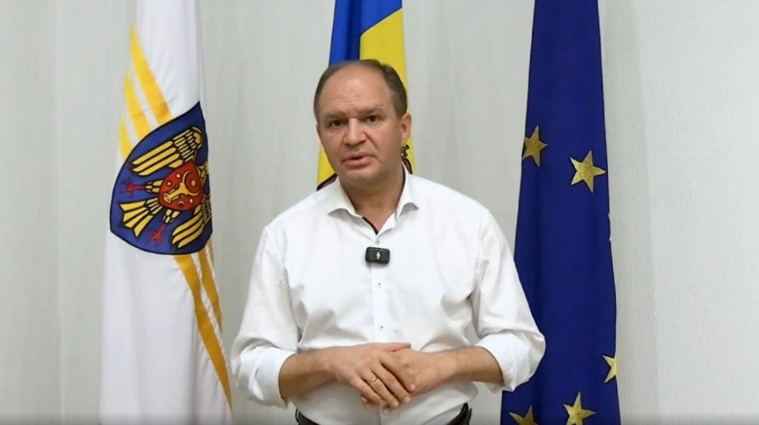Мэр Кишинёва Ион Чебан выступает на фоне герба, национального флага и флага ЕС — озвучивает критическую оценку первых 100 дней правительства Мунтяну