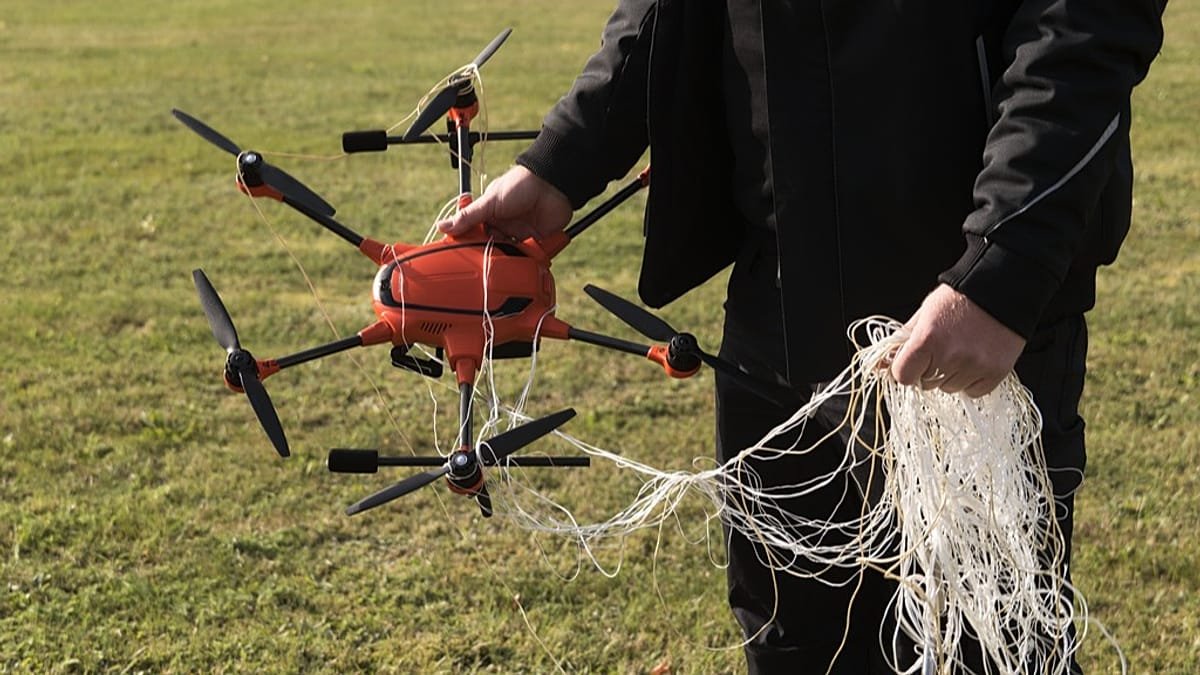 Person holding orange drone tangled in net - hybrid warfare illustration