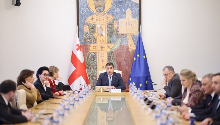 Зал заседаний парламента Грузии с официальными лицами, видны флаги Грузии и ЕС