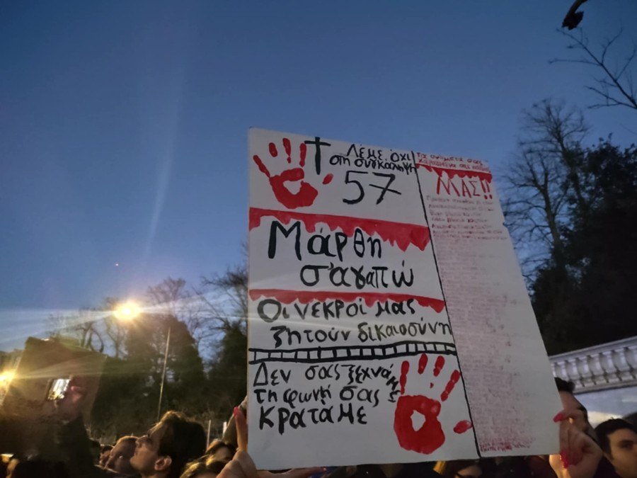 Плакат с кровавыми отпечатками ладоней и текстом на греческом, требующий справедливости для 57 погибших в катастрофе Темпи