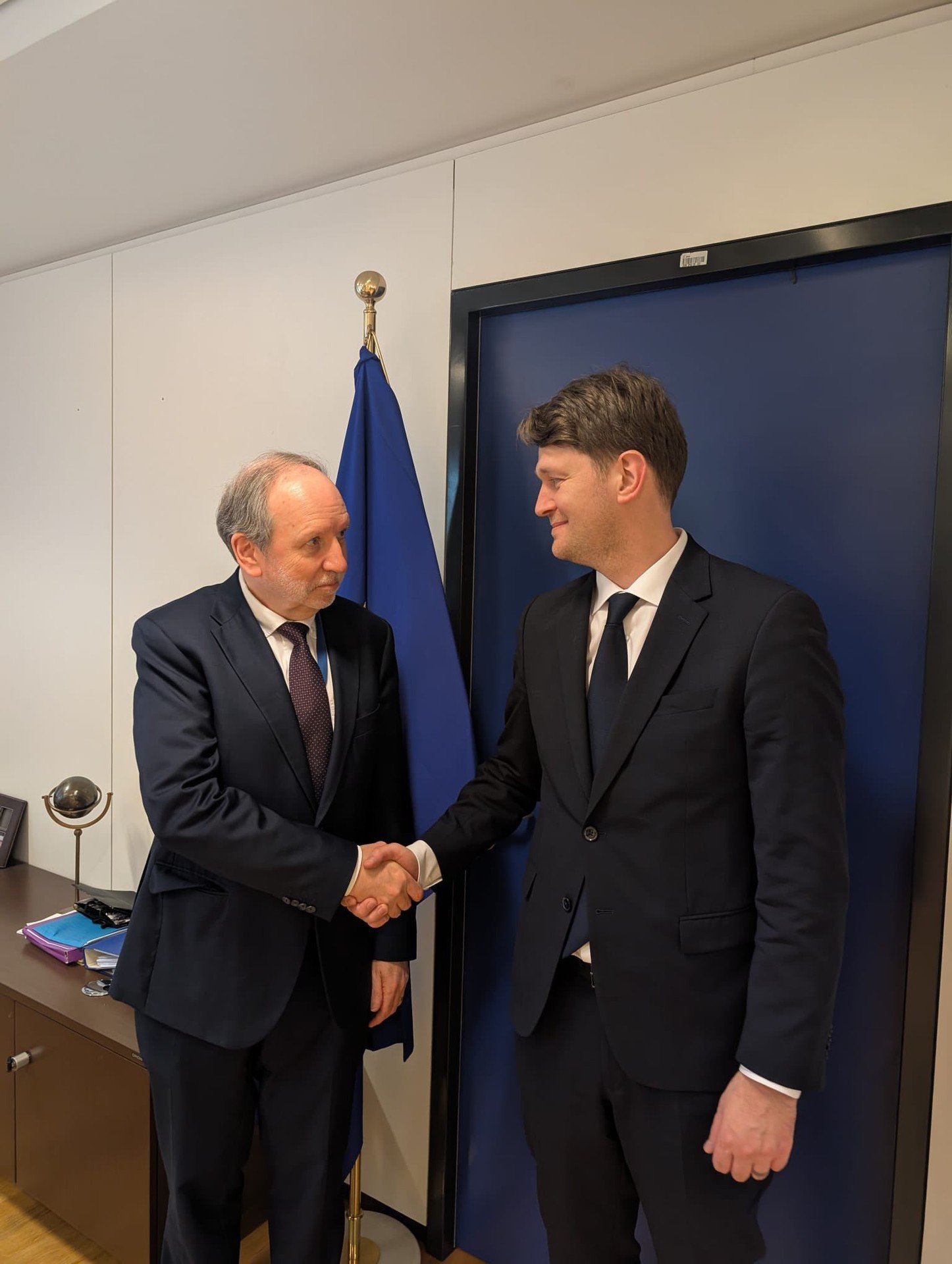 Рукопожатие министра финансов Молдовы и представителя ЕС, флаг ЕС на заднем плане