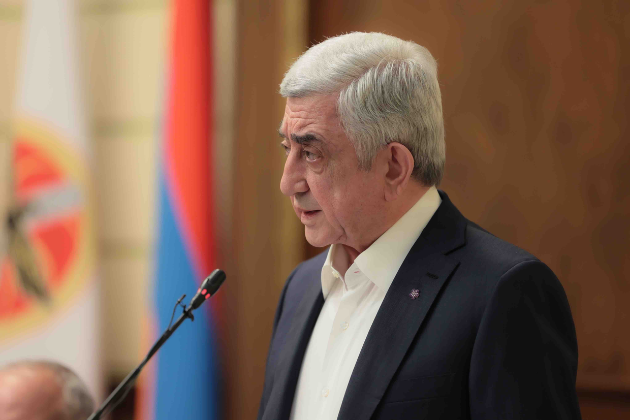Former President Serzh Sargsyan speaking at podium with Armenian flag - key opposition figure