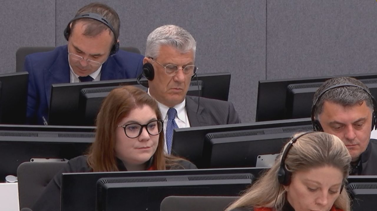 Hashim Thaci wearing headphones in the courtroom, flanked by legal team members, during a hearing at the Kosovo Specialist Chambers