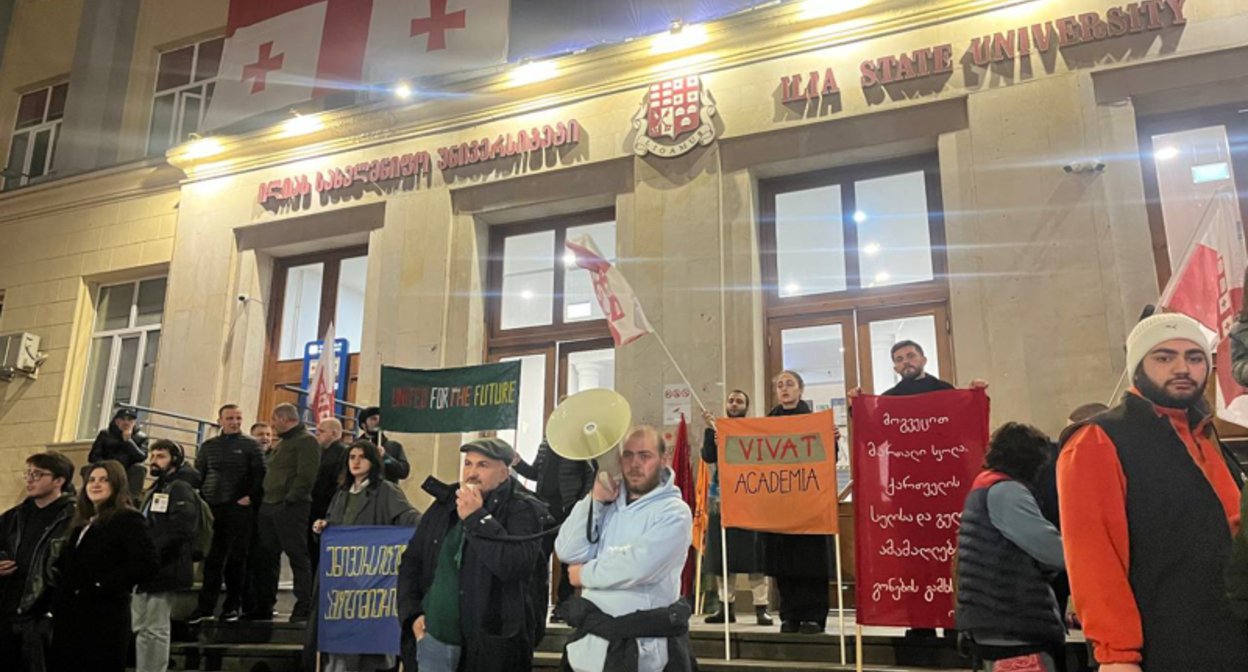 Студенческий протест у Государственного университета Ильи в Тбилиси, активисты с мегафонами и плакатами 'United for the Future' и 'Vivat Academia'