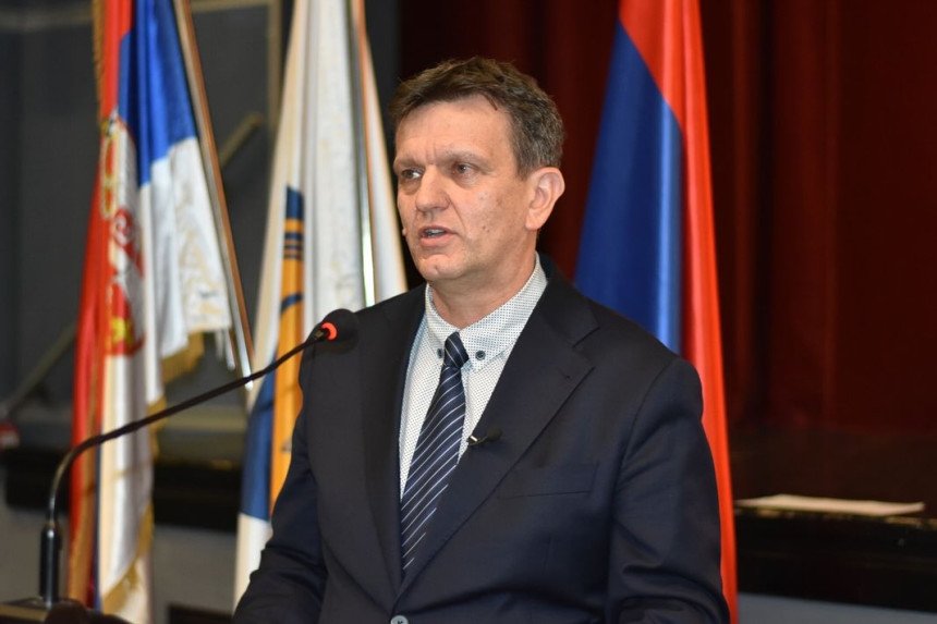 Оппозиционный кандидат Александар Блануша выступает за трибуной, на заднем плане — флаги Республики Сербской и Сербии