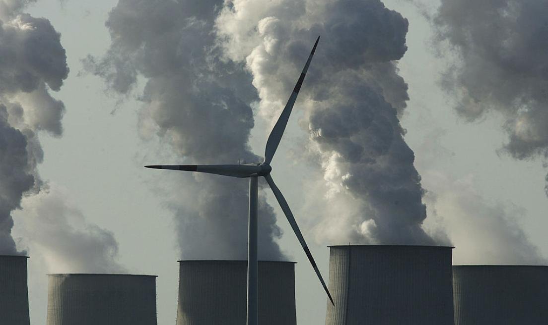 Ветряная турбина на фоне градирен электростанции