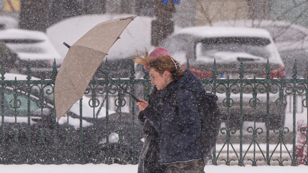 Женщина с зонтом идёт под сильным снегопадом — атмосферный снимок, передающий суровую непогоду