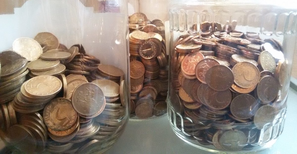 Монеты в стеклянных банках, символизирующие сбережения