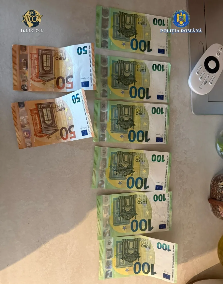 Изъятые банкноты евро (номиналом 50 и 100) на столе с логотипами DIICOT и Полиции Румынии