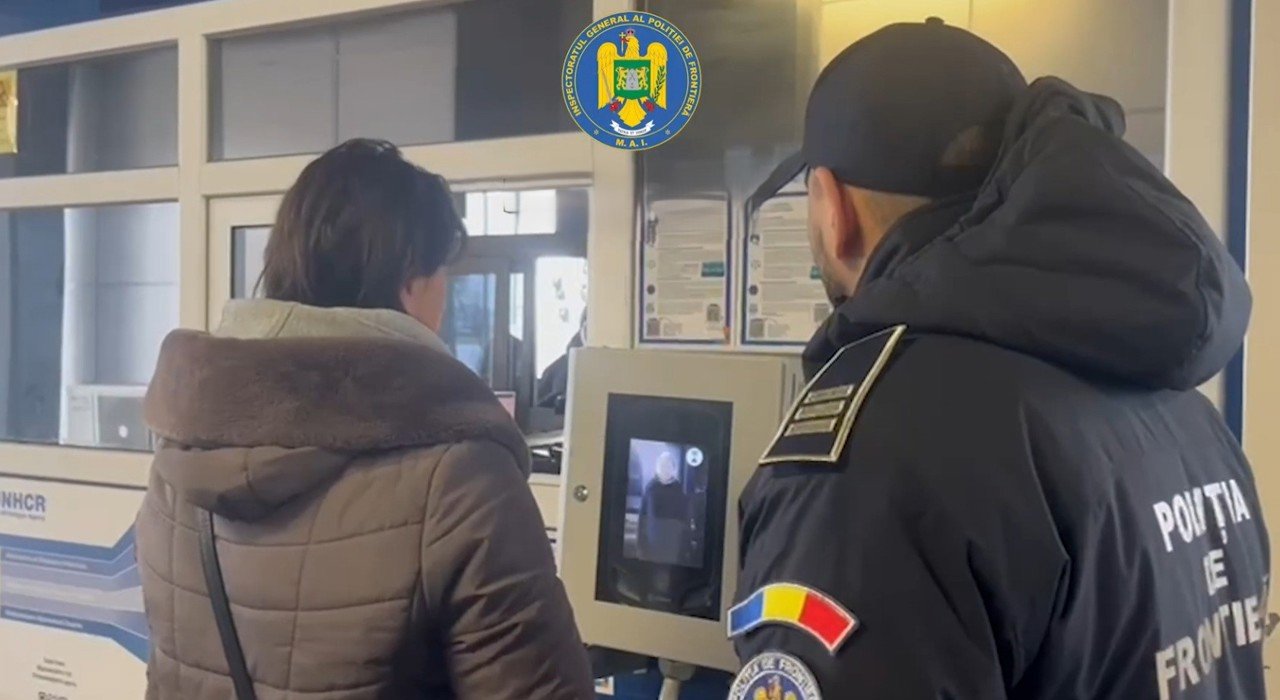 Сотрудник пограничной полиции Румынии помогает путешественнику у терминала самообслуживания EES с распознаванием лиц