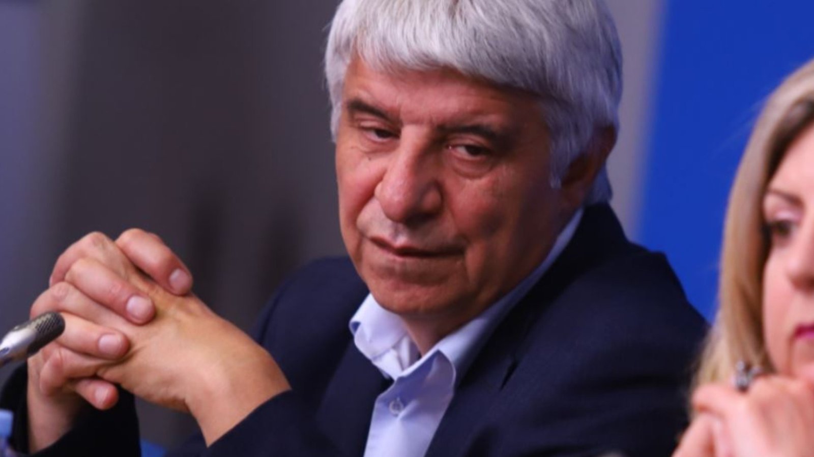 Man speaking at press conference with microphone, likely Prof. Pavlov