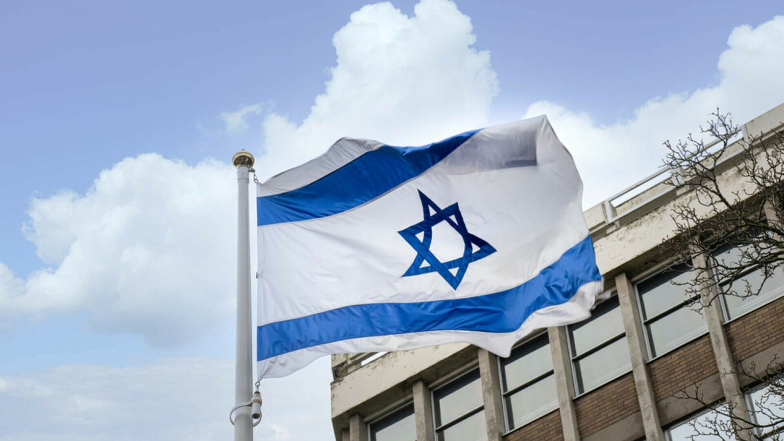 Израильский флаг на фоне голубого неба и здания