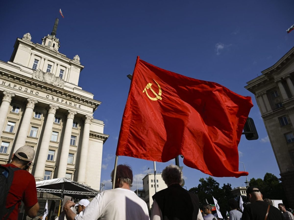 Soviet flag with hammer and sickle waved at protest in front of Bulgarian National Assembly building