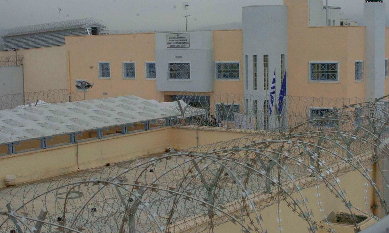 Греческая тюрьма строгого режима с колючей проволокой, сторожевой вышкой, флагами Греции и ЕС