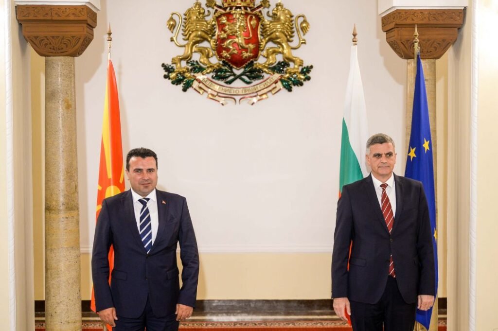 Two officials standing with Bulgarian and North Macedonian flags and Bulgarian coat of arms