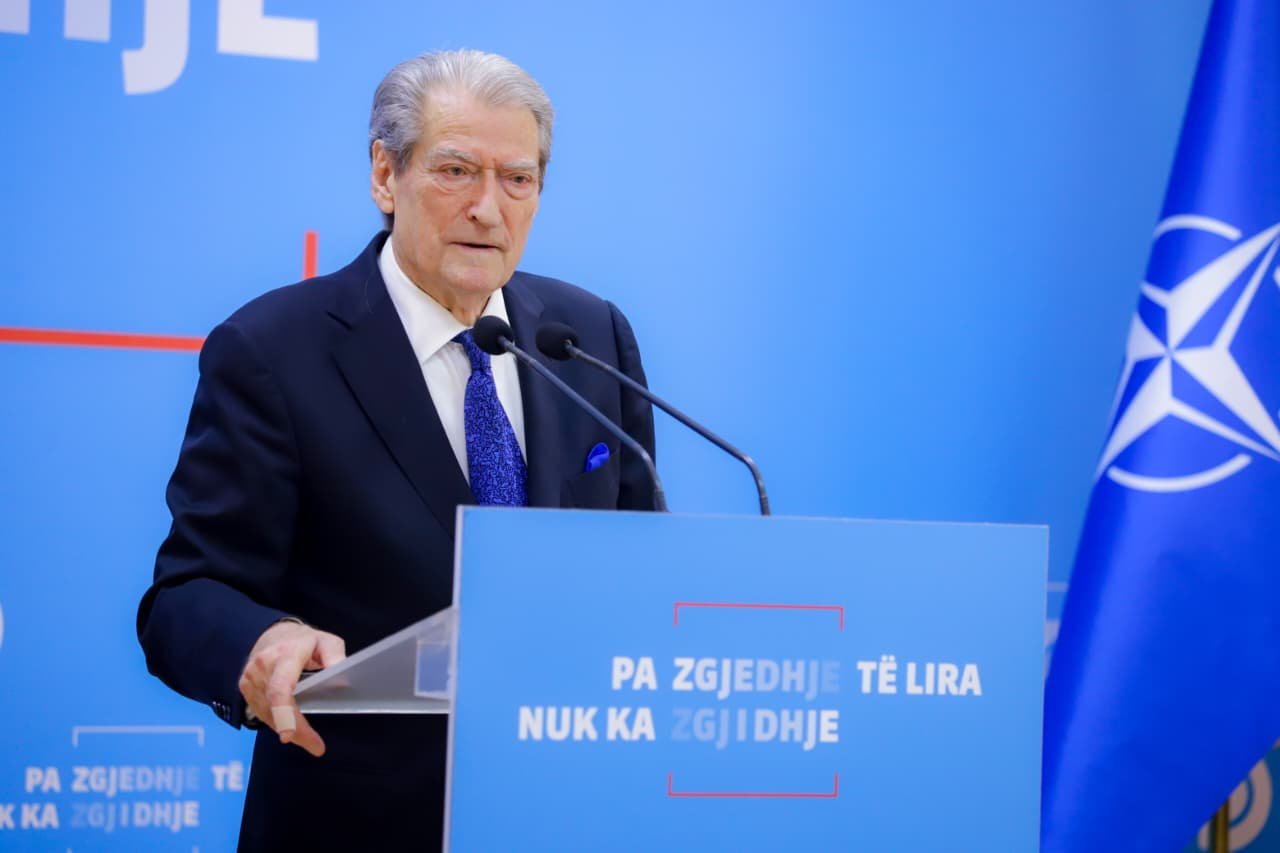 Лидер оппозиции Сали Бериша выступает на трибуне с флагом НАТО