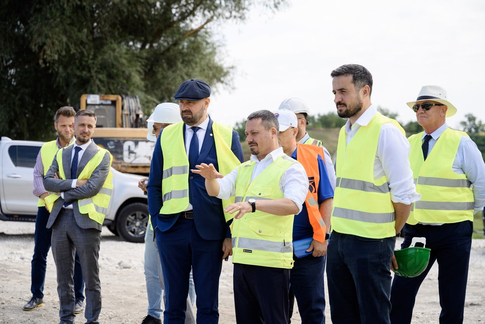 Чиновники в защитных жилетах осматривают строительную площадку инфраструктурного проекта 'Европейское село'