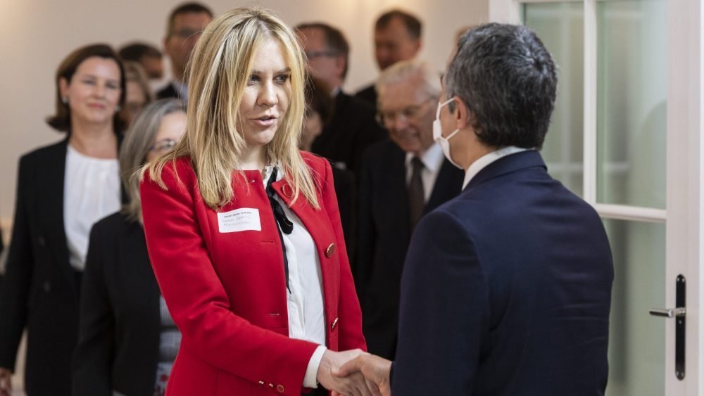 Woman in red jacket at formal diplomatic event