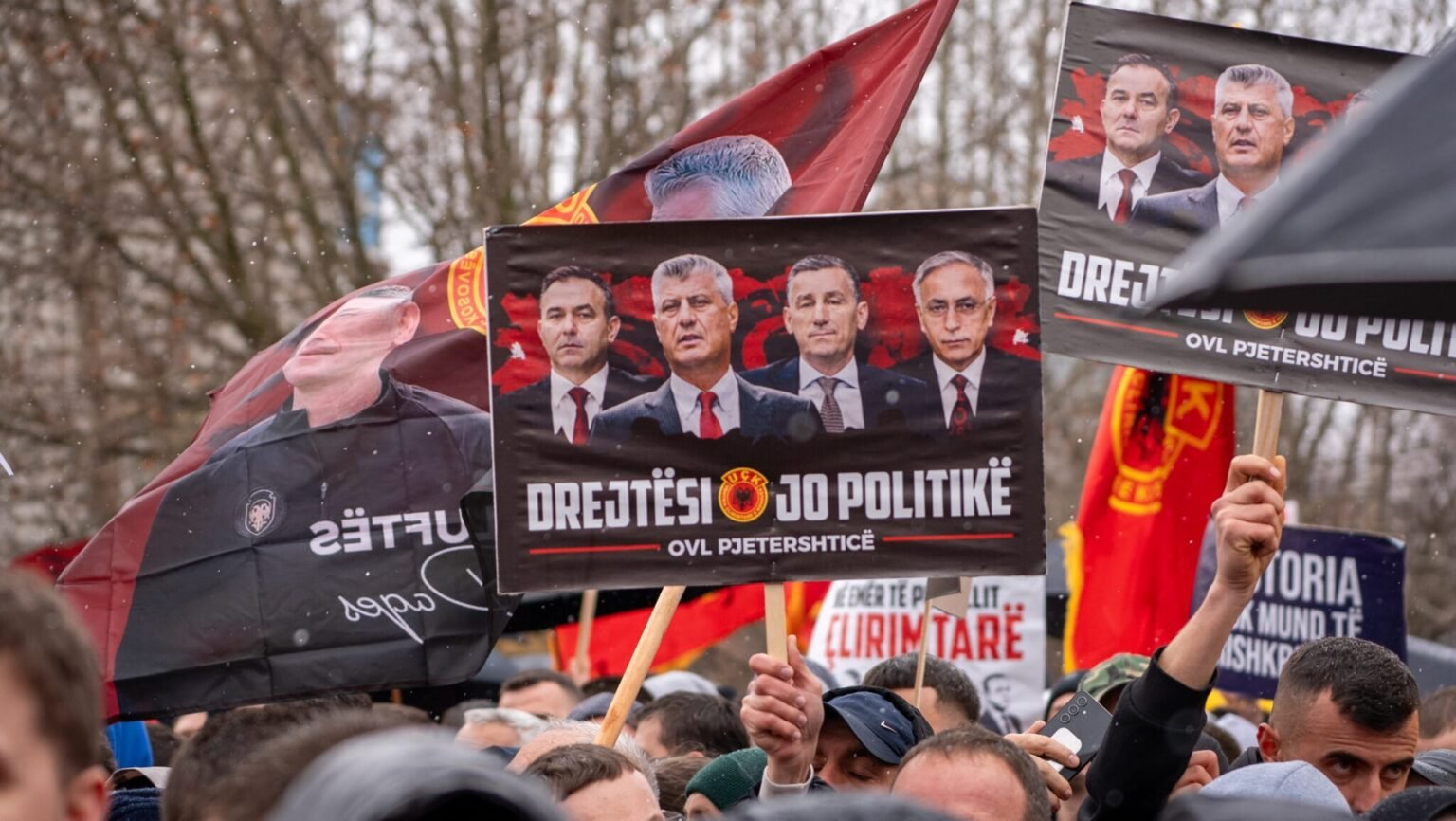 Толпа протестующих с плакатами лидеров АОК (Тачи, Весели, Селими, Краснички) и лозунгом «Справедливость, а не политика»