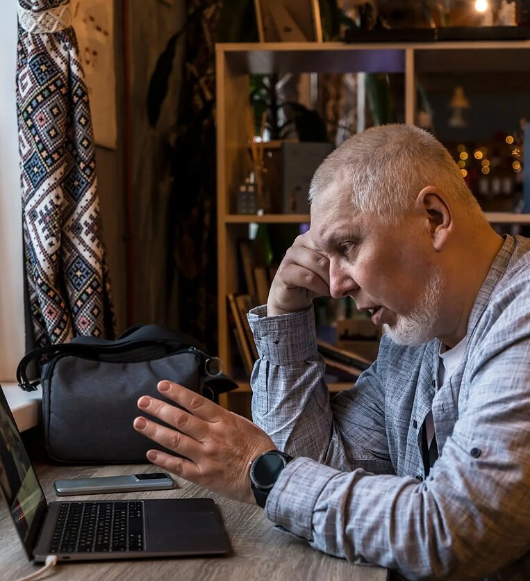 Украинский историк говорит за ноутбуком, жестикулирует рукой, вышиванка на фоне