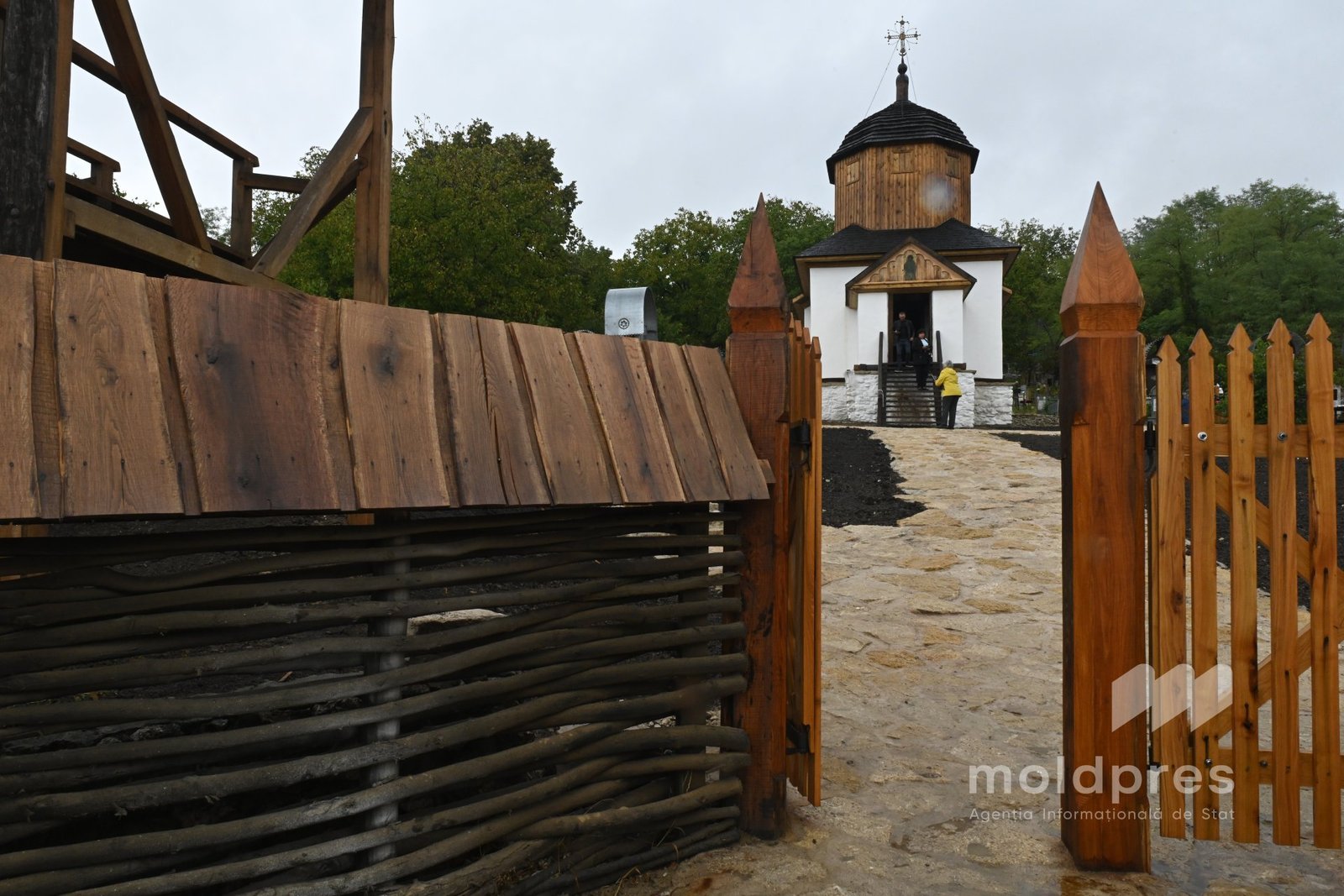 Деревянные ворота на входе в исторический молдавский церковный комплекс с туристами, традиционная архитектура с колокольней