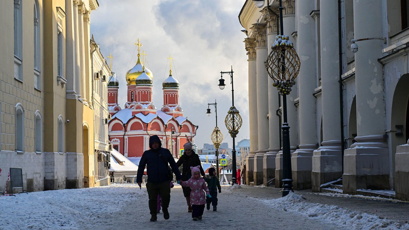 Family walking in snowy Moscow with church in background