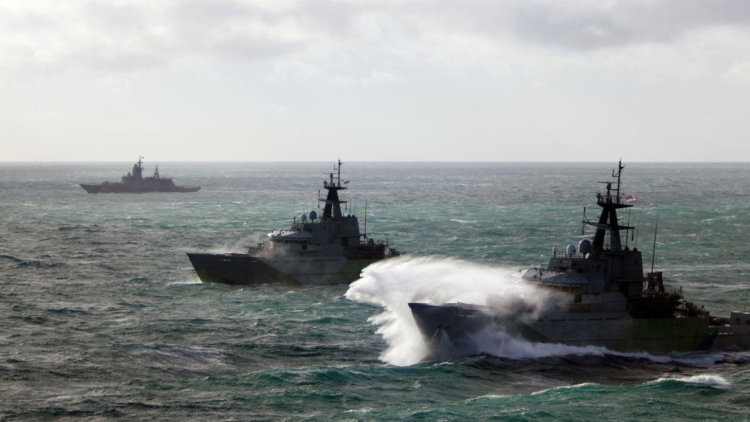 Naval warships at sea with dramatic waves - illustrates NATO/military presence