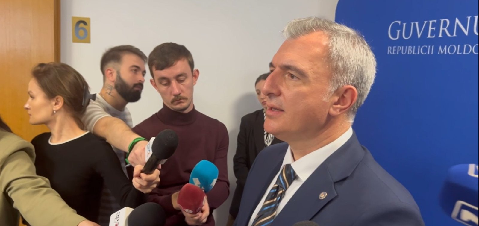 Government official Osmochescu at press conference with Guvernul Republicii Moldova banner
