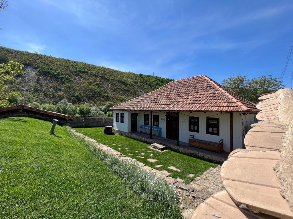 Традиционная молдавская сельская агропансиона в Требужень с белыми стенами, черепичной крышей и зелёными холмами на заднем плане