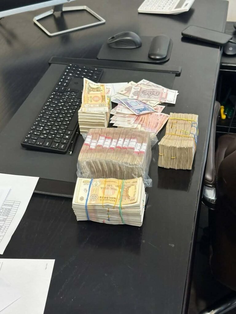Крупные пачки изъятых наличных (молдавские леи) на офисном столе с клавиатурой