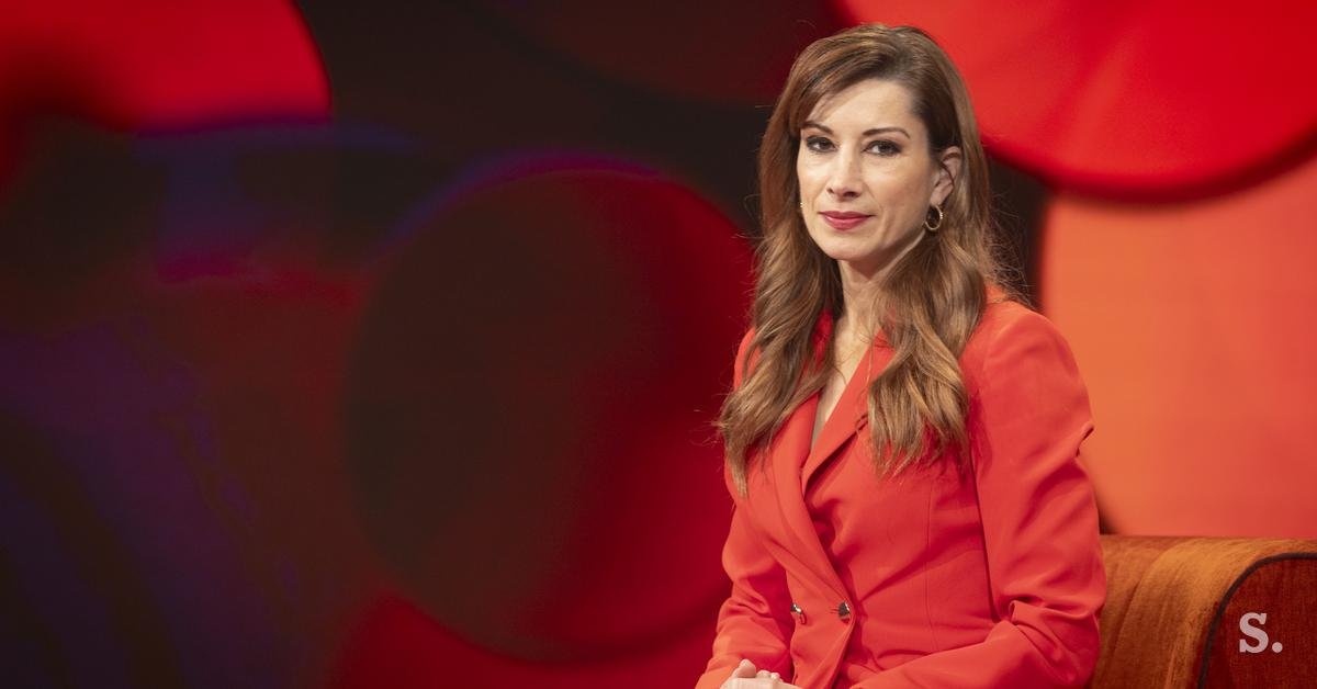 Woman in red blazer in TV studio setting, relevant to media/journalism theme