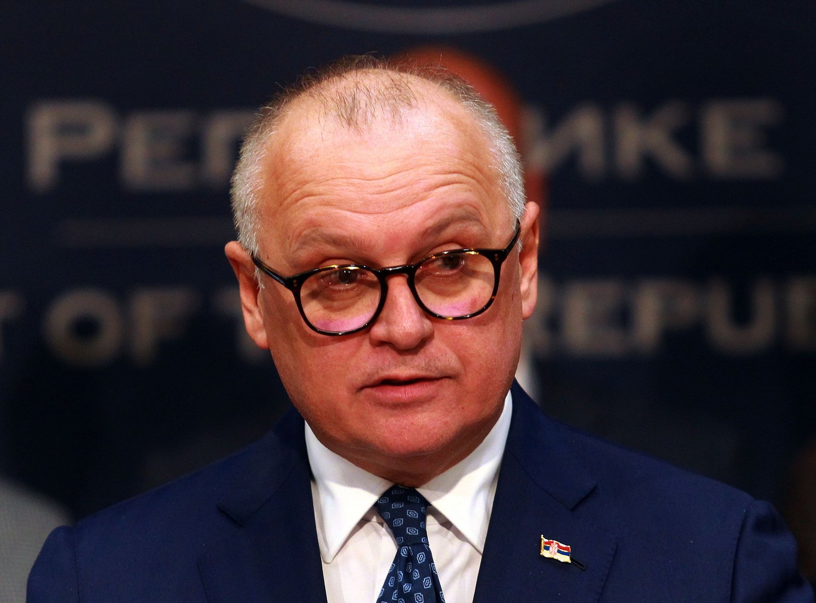 Portrait of official (likely Goran Vesić) in suit with Serbian flag pin