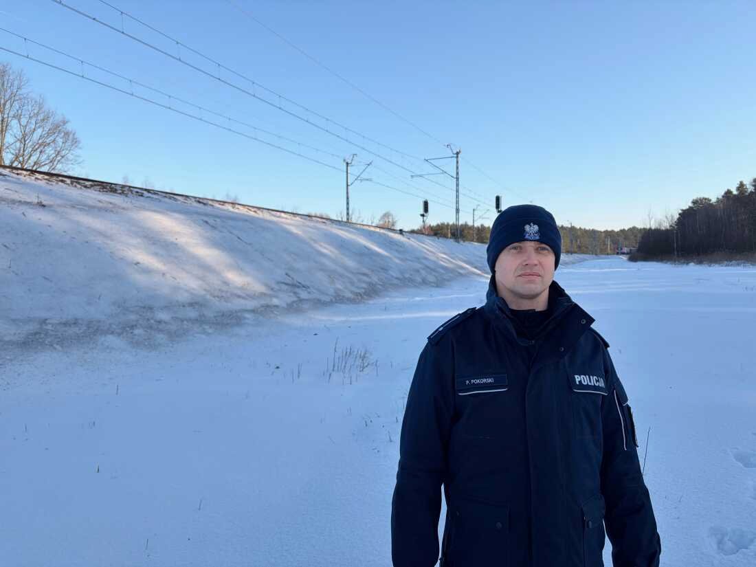 Polish police officer standing in snowy area near railway border zone