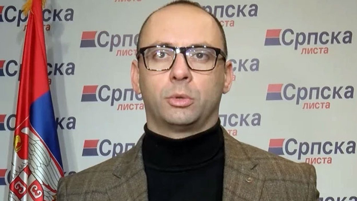 Игорь Симич, депутат от «Сербского списка», выступает на пресс-конференции на фоне сербского флага