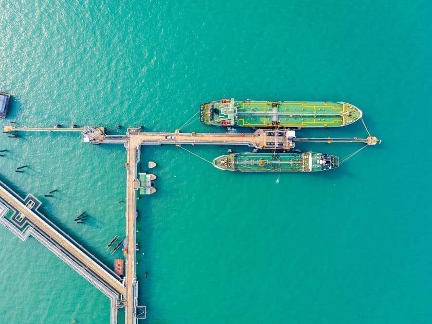 Вид сверху на два нефтяных танкера у погрузочного пирса, бирюзовая морская вода